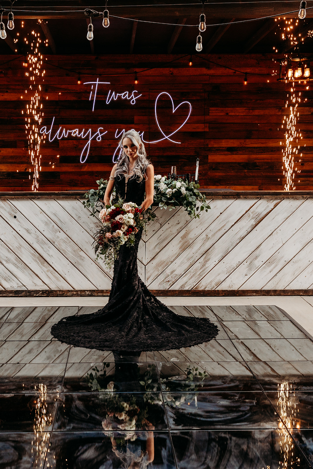 lgbtqia gothic wedding in phoenix arizona at the venue at chileens in black wedding dress with neon sign in background