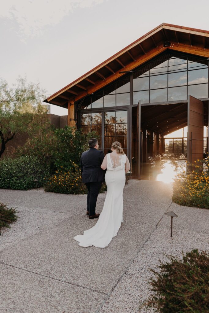 plus size bride wearing vneck crepe sheath wedding dress with husband in dark suit walking in front the paseo wedding venue