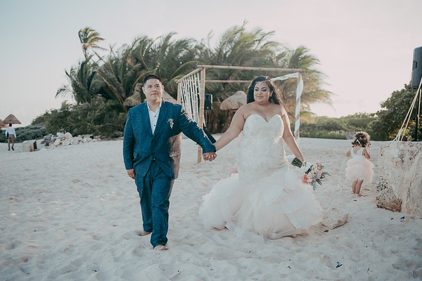 curvy bride wearing dazzling plus size mermaid wedding gown holding groom's hand.