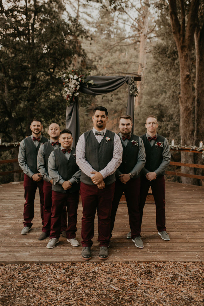 Groomsmen in vests and maroon pants. 