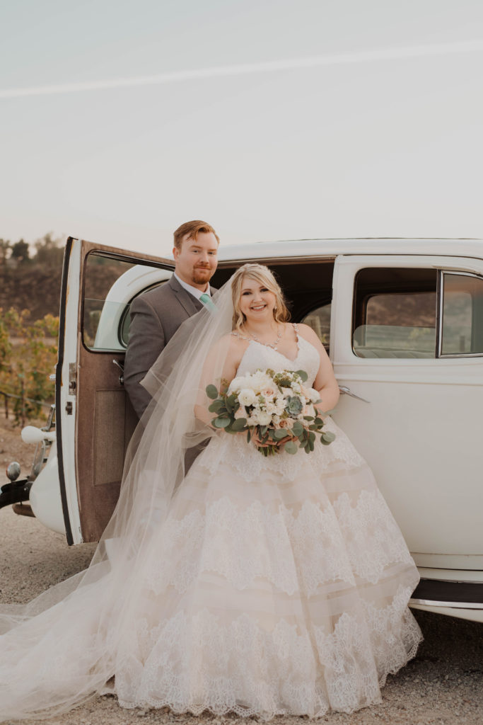 newlyweds in front of vintage car plus size bride