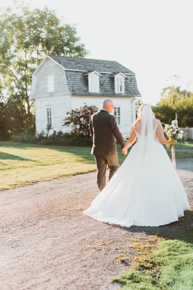 back of bride in plus size 3D lace wedding dress holding groom's hand