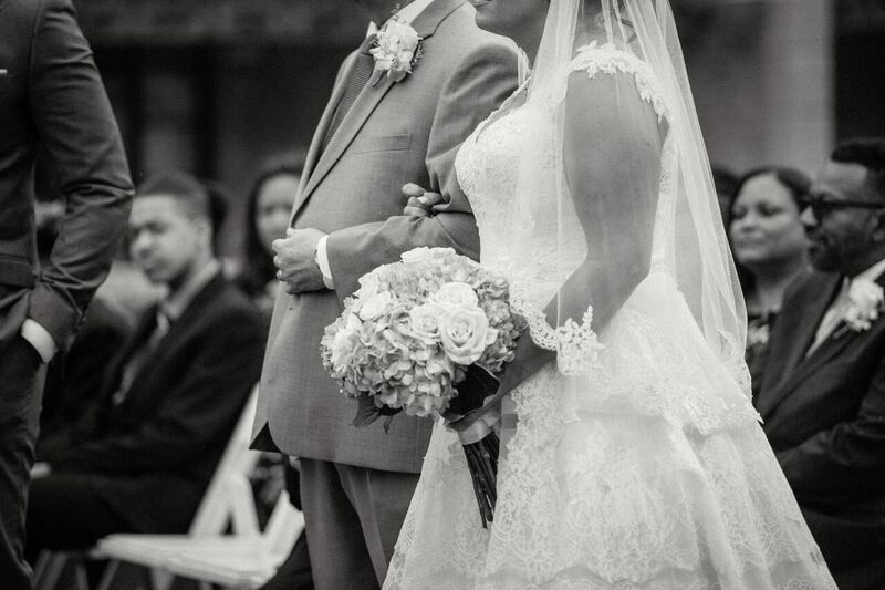 black and white photo of curvy bride in  show stopping a line wedding dress walking down the aisle