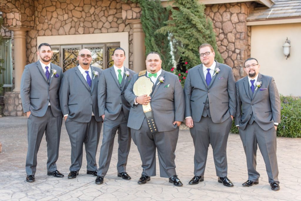 groom wears wrestling belt with groomsmen in suits