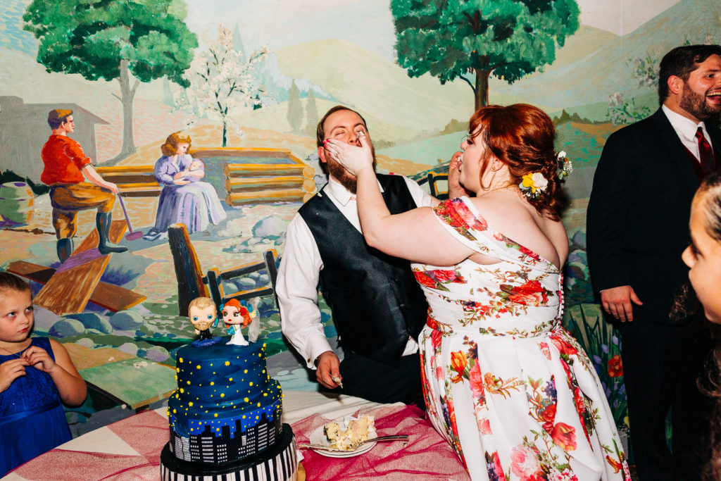 newlywed couple smashing cake in their faces