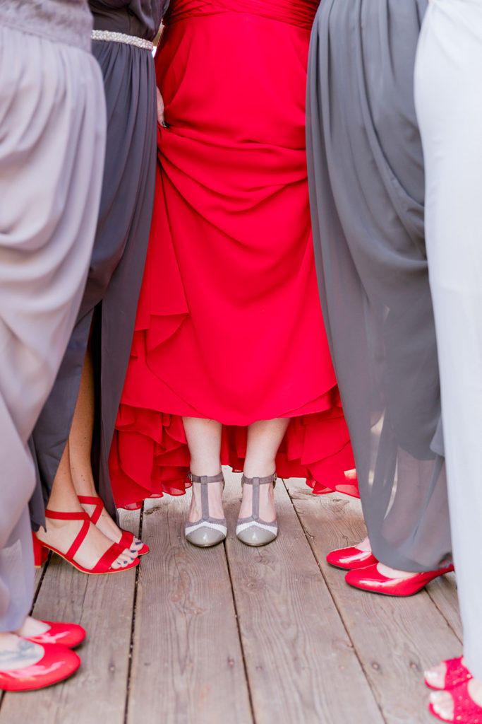 bridesmaids wearing red shoes and gray dresses with bride in custom red wedding dress