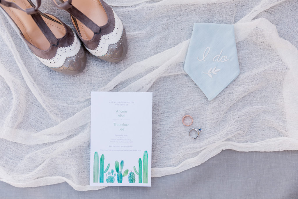 flatlay image of wedding shoes invitation rings and handkerchief