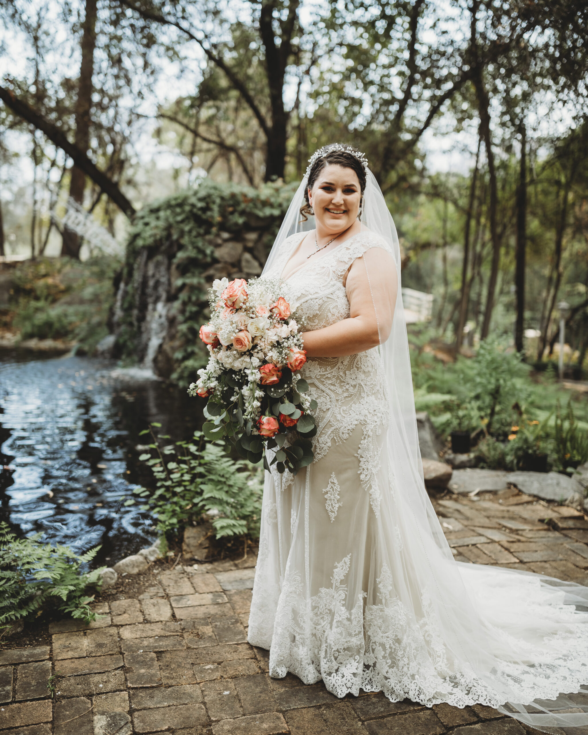 Beautiful plus size bride on wedding day smiling with lace dress in nature by waterfall in long beach califorfnia