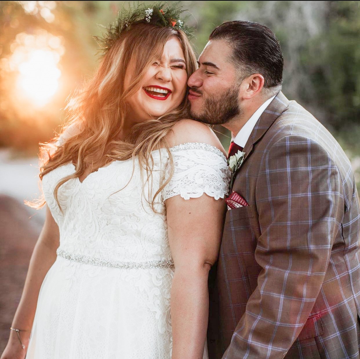 bride wearing wedding dress with off the shoulder sleeve kissing groom