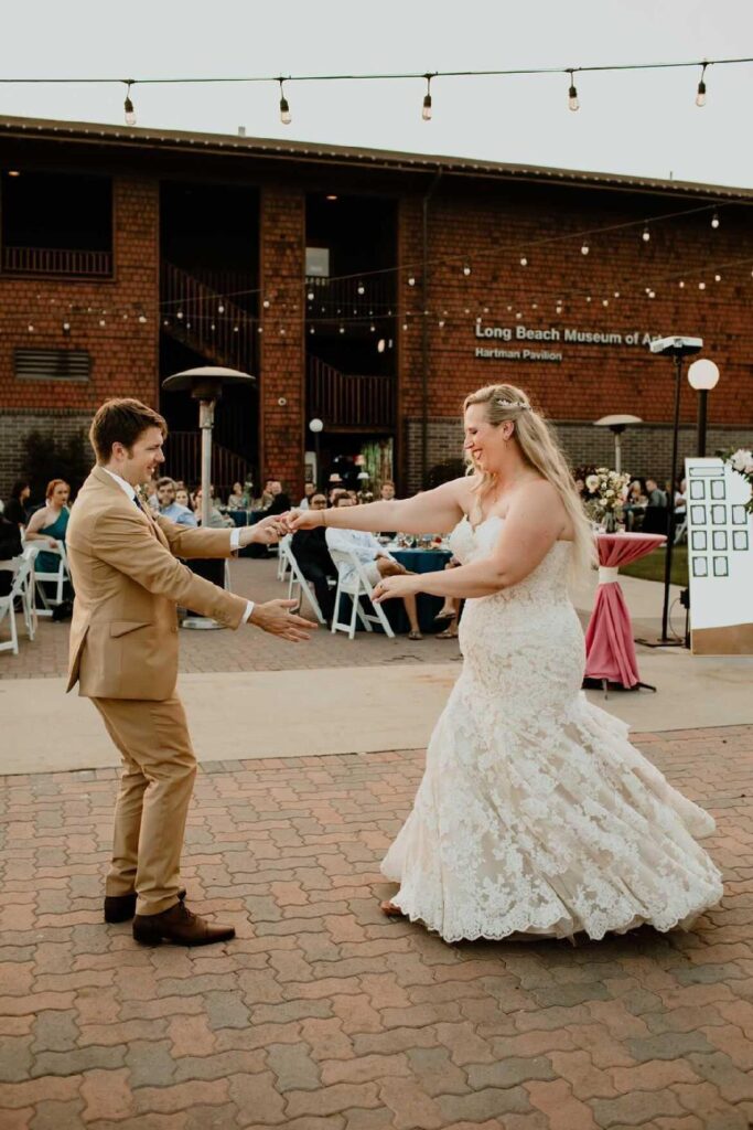 bride wearing two tone champagne lace mermaid wedding dress and groom in tan suit dancing