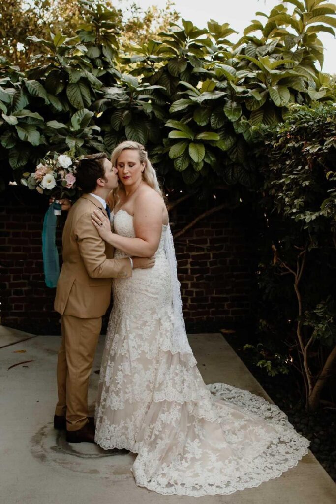 bride wearing two tone champagne lace mermaid wedding dress and groom in tan suit