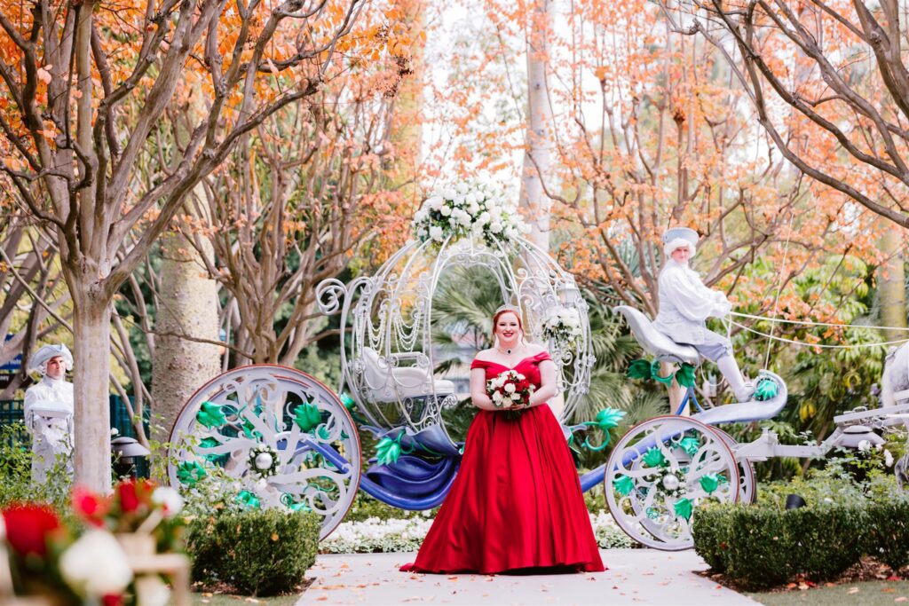 bride in red wedding dress in front of cinderella's carriage