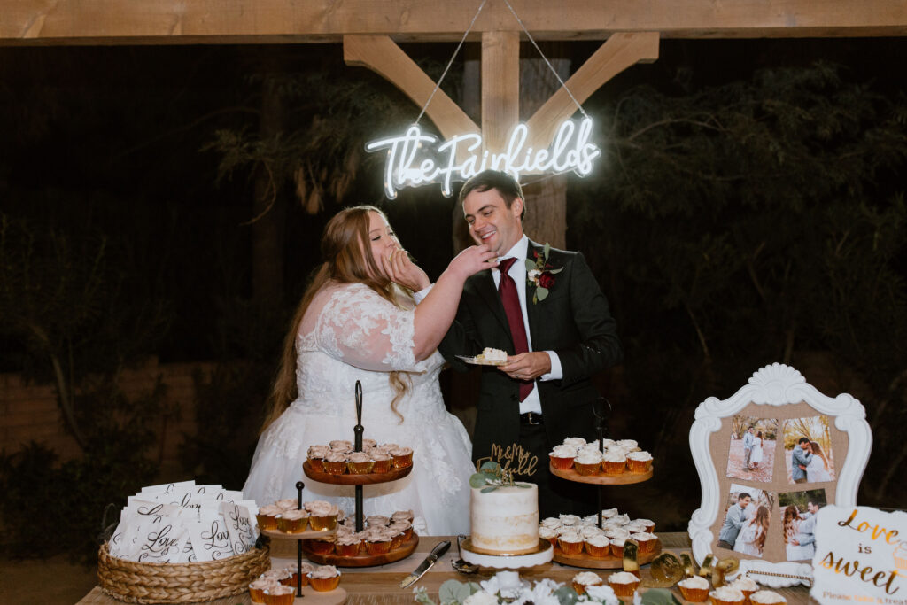 bride and groom at dessert table with neon sign