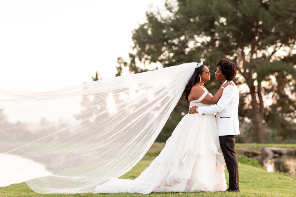 black bride and groom walking on golf course with long cathedral veil