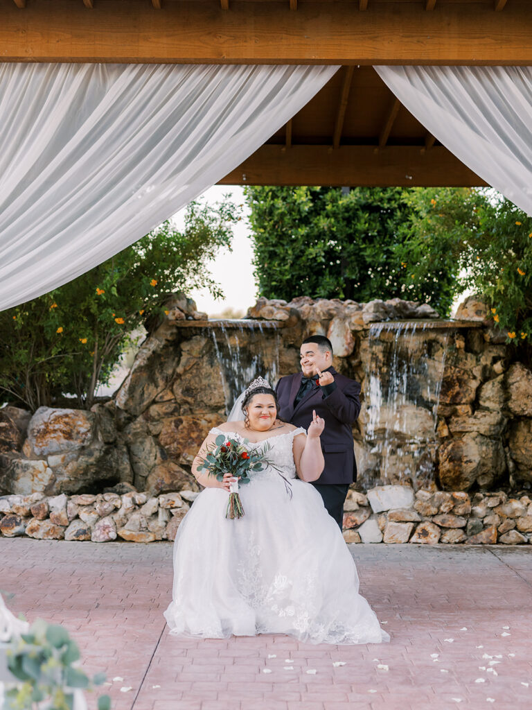 plus size bride sitting with groom in front of waterfall