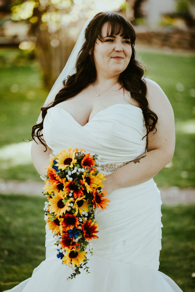 plus size bride in ruffled mermaid wedding dress with large sunflower bouquet