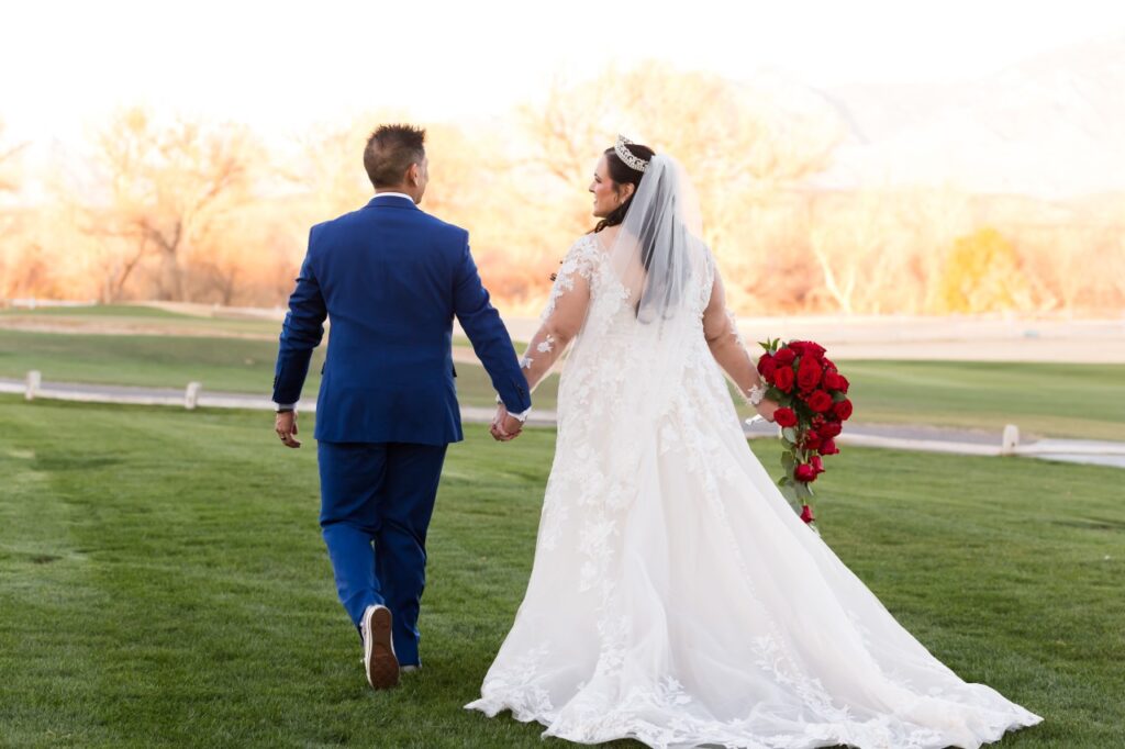 plus size bride holding red roses with groom in blue suit