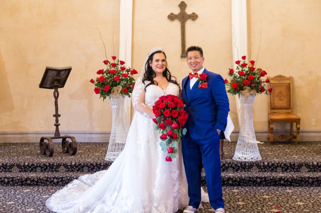 bride holding red roses with groom in blue suit