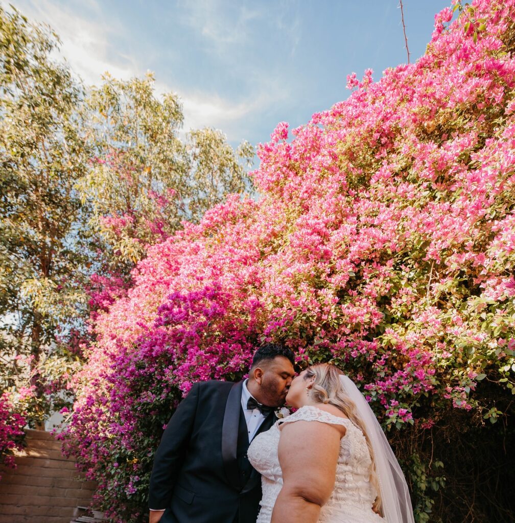 plus size bride and groom kissing under tree with pink flowers