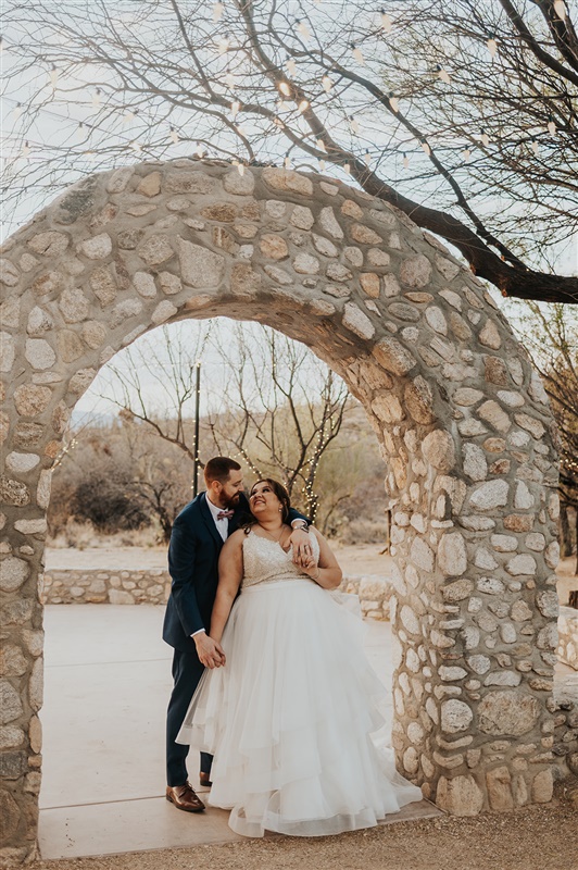 bride and groom standing under stone arch