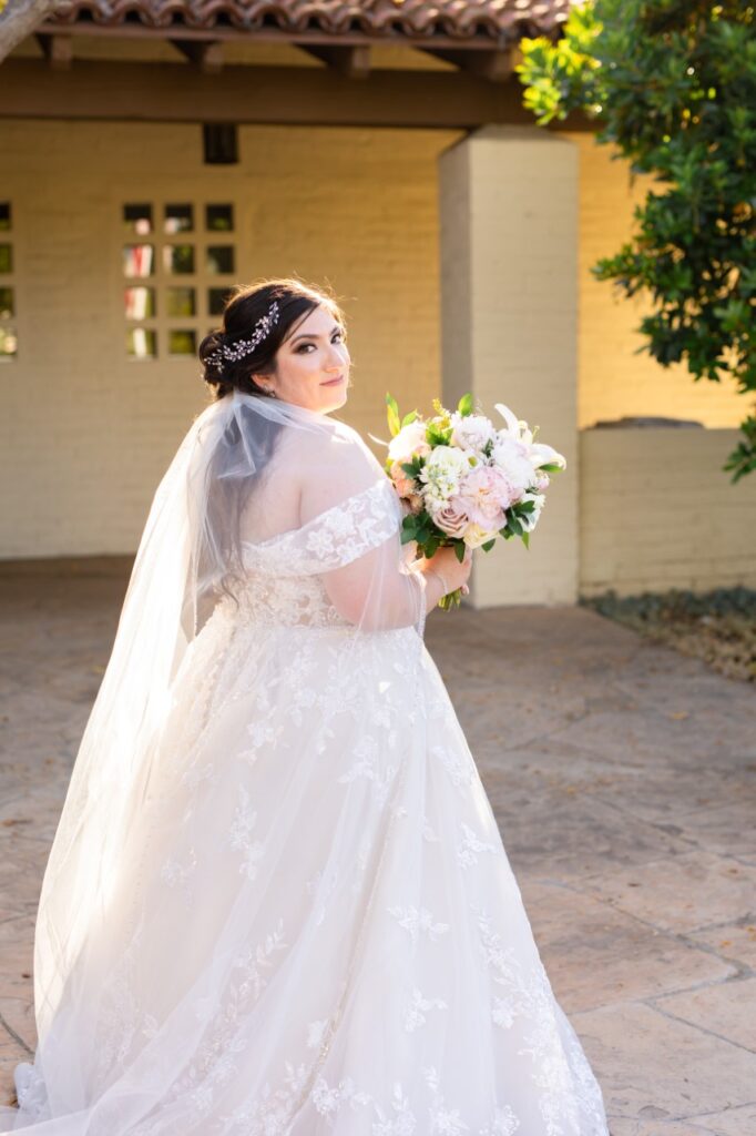 bride wearing off the shoulder lace ballgown holding flowers