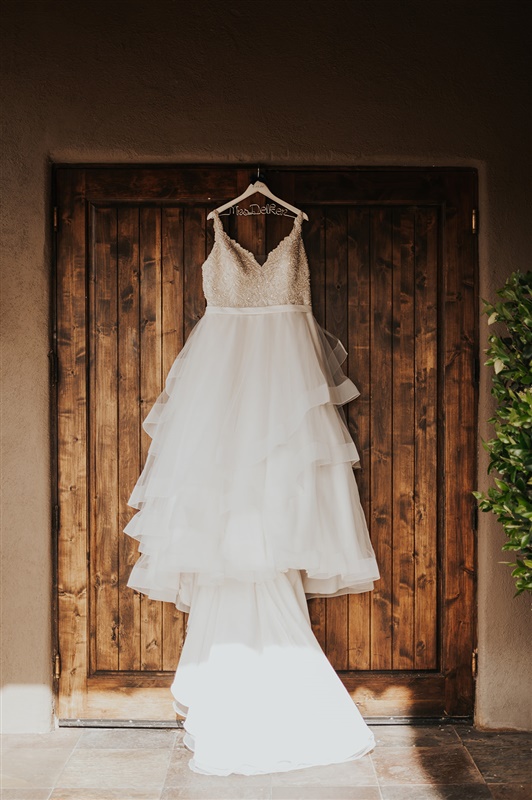 beaded bodice ruffled wedding dress hung on door