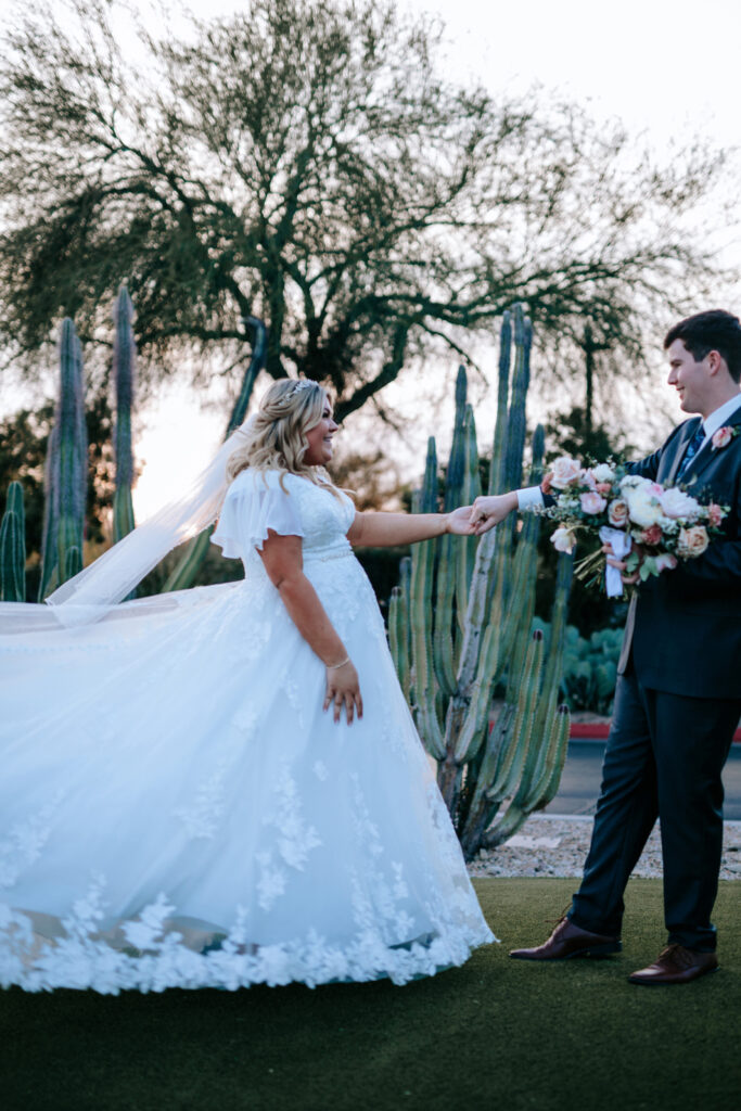 bride wearing modest wedding dress with groom in tux on grass in mesa arizona