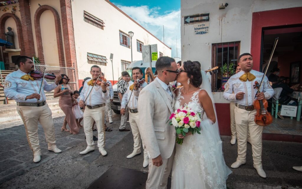 bride and groom kissing on the street in front of mariachi band