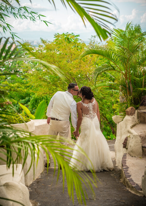 bride wearing lace mermiad dress with groom surrounded by exotic green plants