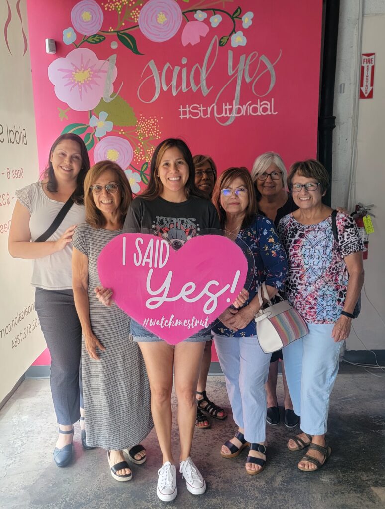 bride with family holding i said yes sign long beach california bridal shop
