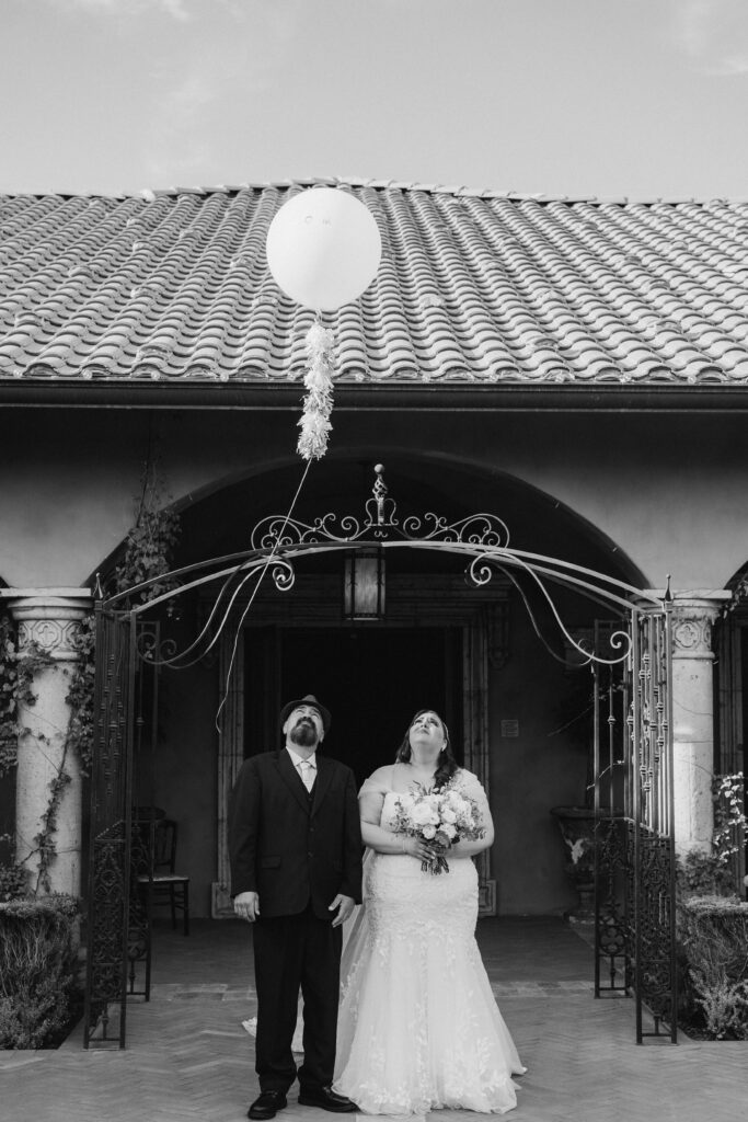 plus size bride and groom looking up at a balloon