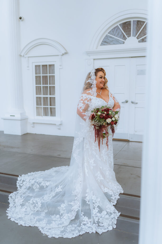 plus size bride wearing long sleeve lace fitted wedding dress with long dramatic lace train long beach california