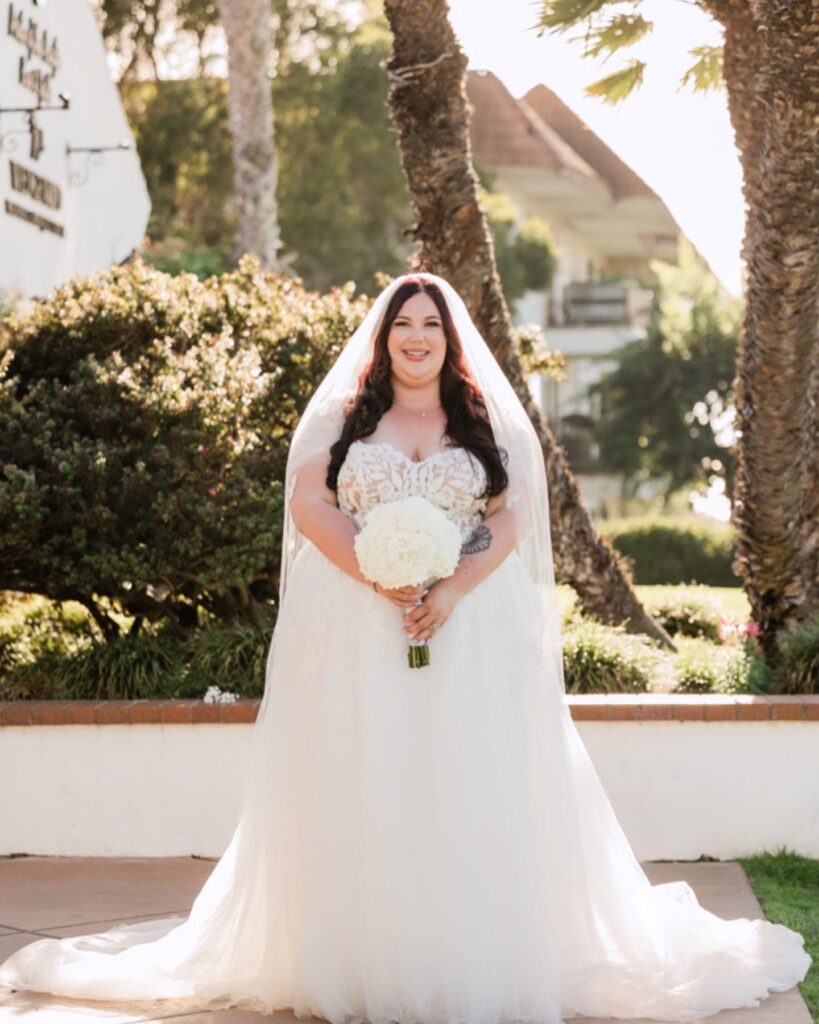 plus size bride wearing lace and tulle classic aline wedding dress holding white wedding bouquet