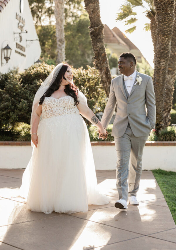 plus size bride wearing lace and tulle classic aline wedding dress holding white wedding bouquet groom in gray suit