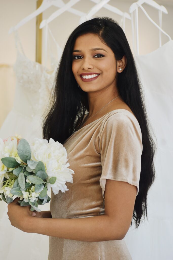 girl wearing velvet bridesmaid dress in chandler arizona bridal shop holding a bouquet of white flowers