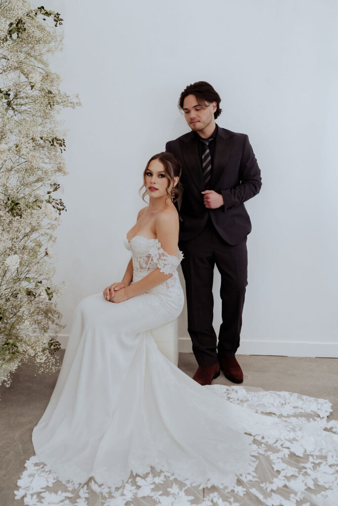 bride wearing sexy crepe wedding dress with large lace train, groom in dark suit chandler arizona bridal shop