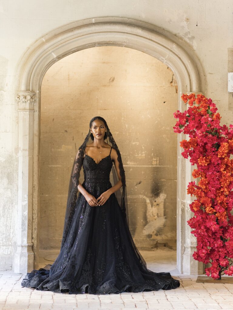 petite bride wearing lace aline black wedding dress near red flowers