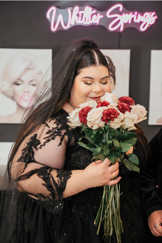 plus size bride wearing long sleeve black lace wedding dress holding a wedding bouquet