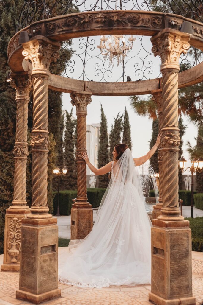 bride wearing off the rack ruffled aline wedding dress standing by pillars